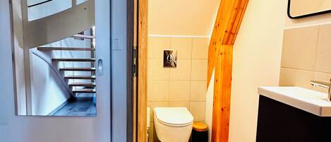 Un baño moderno con una escalera de madera, un inodoro y un lavamanos.