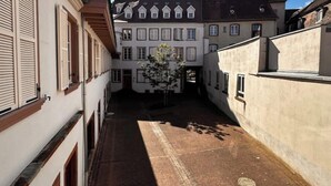 Un stretto vicolo fiancheggiato da edifici, con un albero al centro e cielo sereno.