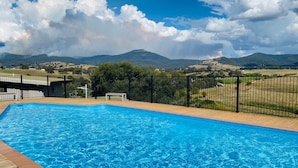 A swimming pool with a wooden deck and a black metal fence. - Delatitie Apartments -Cedar 1 Bedroom Apartment - Merrijig (Merrijig)