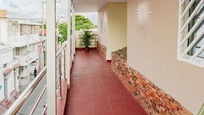 Un couloir doté d’un sol carrelé de carreaux rouges, d’une plante en pot et d’un mur orné d’un motif solaire.
