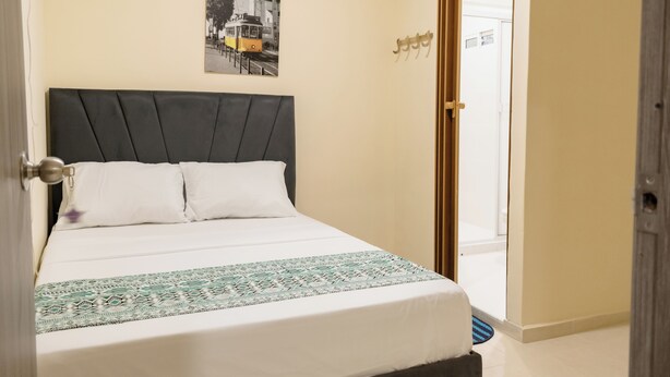 Une chambre d’hôtel avec un lit, une porte, une photo accrochée au mur et une pancarte au-dessus de la porte.