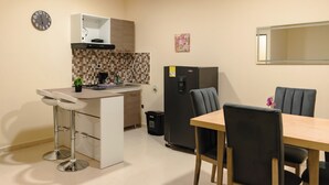 Une cuisine compacte avec un coin repas, comprenant un réfrigérateur, un évier et un petit tabouret de bar.