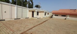 Un patio empedrado con varios edificios, cada uno con una entrada diferente y un pequeño porche.