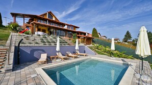A modern house with a swimming pool, outdoor seating, and a hillside garden. - Beautiful home in Falinic Breg with sauna (Falinic Breg)