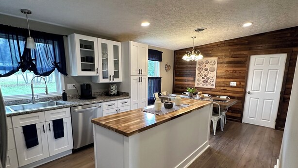 A modern kitchen with a central island, white cabinetry, and wooden flooring. - Route 66 Rails to Trails home with Central AC and WIFI (Shippenville)