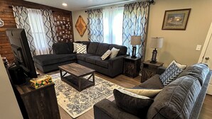 A modern living room with a sectional sofa, a coffee table, and a TV. - Route 66 Rails to Trails home with Central AC and WIFI (Shippenville)