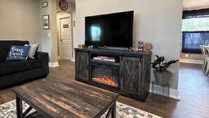 A living room with a fireplace, a television, a sofa, and a coffee table. - Route 66 Rails to Trails home with Central AC and WIFI (Shippenville)