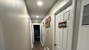 A hallway with wooden flooring, white walls, and a ceiling light. There is a sign on the wall that reads "Laundry Room". - Route 66 Rails to Trails home with Central AC and WIFI (Shippenville)