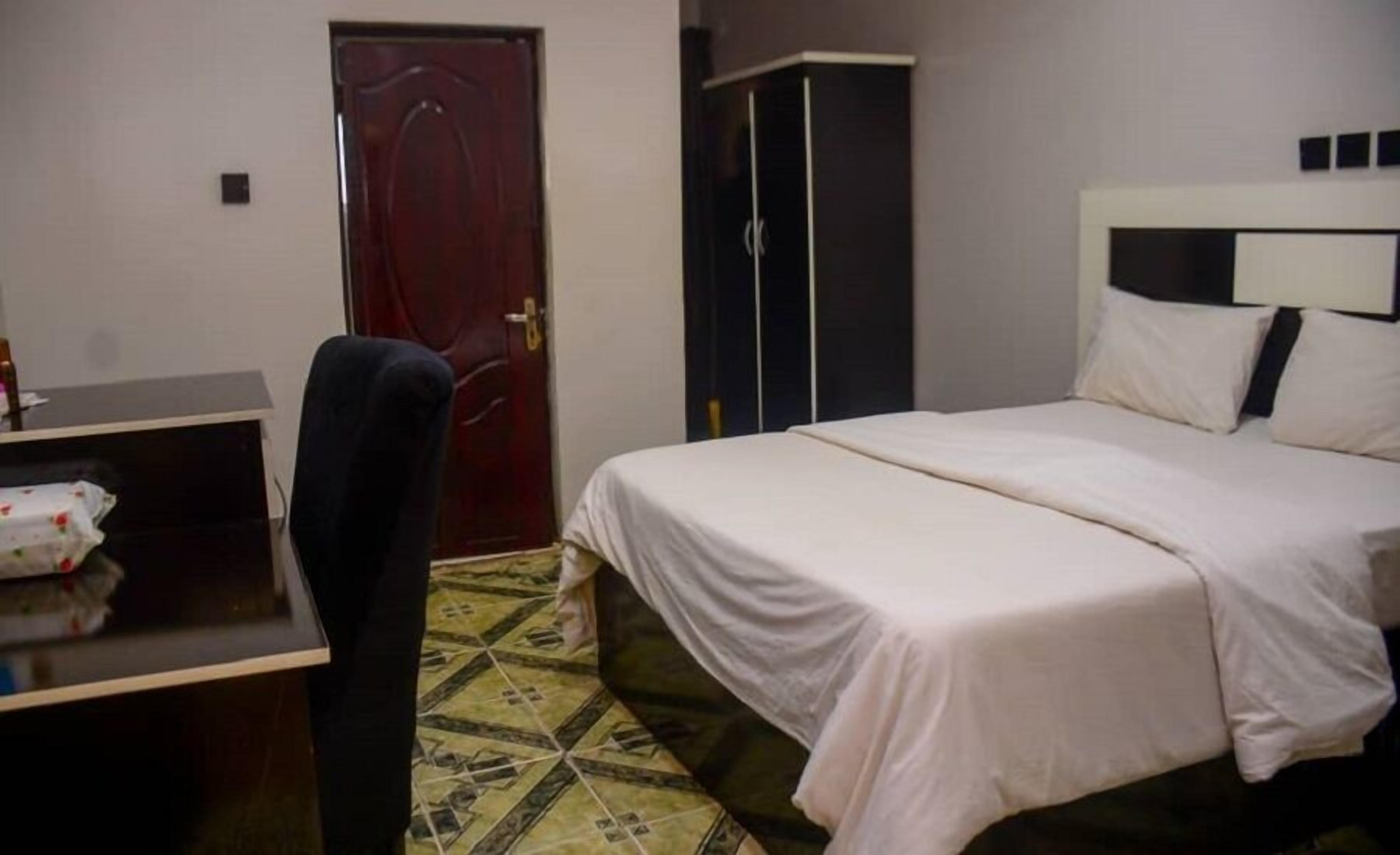 Una habitación de hotel con cama, escritorio, silla y armario.