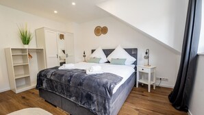 Un dormitorio con cama, armario, mesita de noche y una planta.