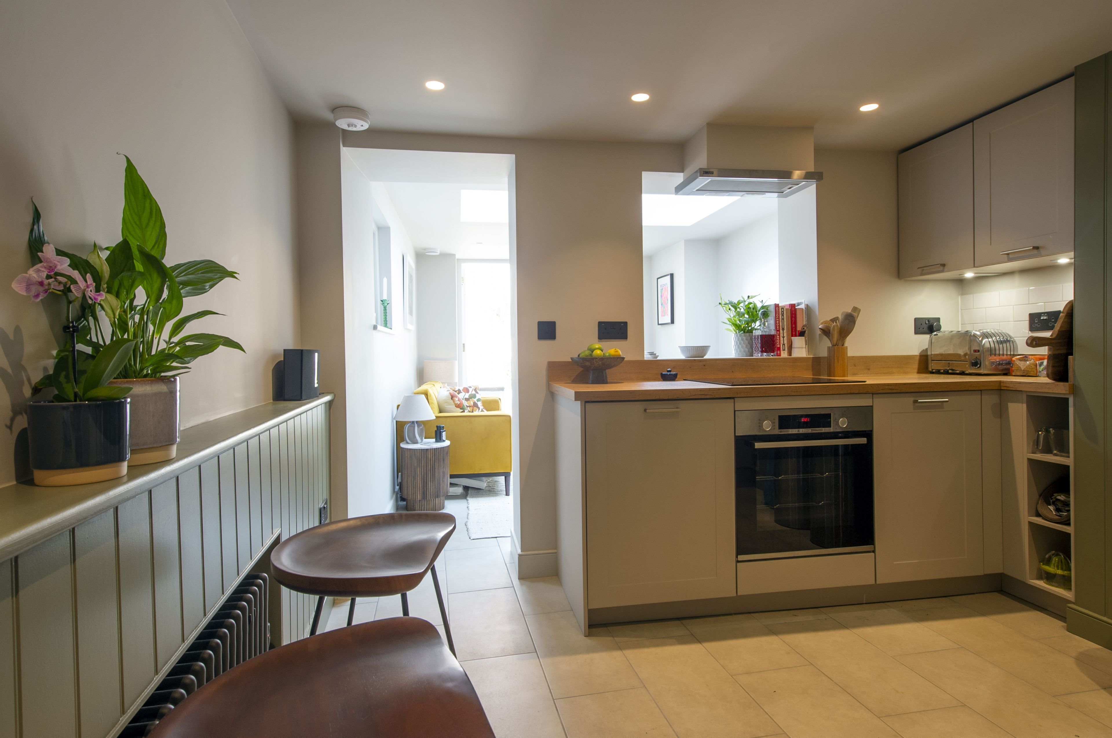 A modern kitchen with a central island, built-in oven, and a dining area with a bench.
