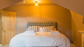 A bedroom with a large bed, a wooden door, and a ceiling light. - Sea to Sea, Hythe Kent (Hythe)