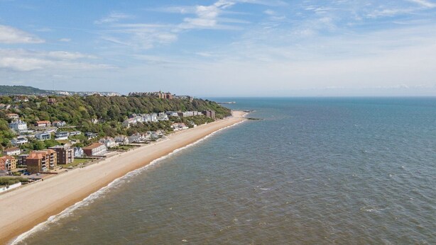 A coastal view with a beach and buildings along the shore. - Sea to Sea, Hythe Kent (Hythe)
