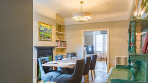 A dining area with a wooden table, upholstered chairs, and a chandelier. - Sea to Sea, Hythe Kent (Hythe)