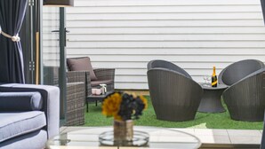 Un espace patio aménagé avec des meubles en osier, une table en verre et un vase rempli de fleurs.