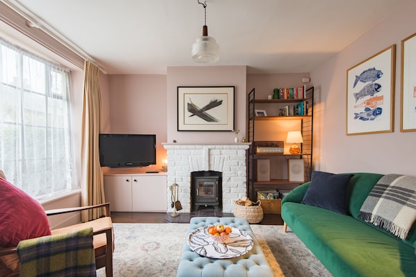 A cozy living room with a fireplace, a television, a sofa, and a coffee table with fruit. - Seafarer, Kingsdown Kent (Kingsdown)