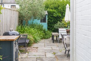 A patio area with stone flooring, outdoor furniture, a blue shed, and a white umbrella. - Seafarer, Kingsdown Kent (Kingsdown)