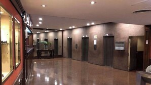Un vestíbulo amplio con piso pulido, una recepción y varios ascensores.