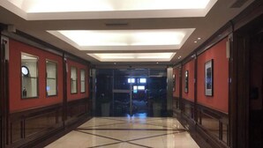 Un vestíbulo de hotel con piso pulido, paredes rojas y un ascensor de vidrio.