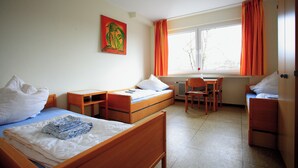 A room with two single beds, a desk, a chair, and a radiator. - BOLA Kulturhostel (Bochum)