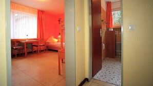 A room with a bed, a desk, and a chair. There is a window with curtains and a radiator on the wall. - BOLA Kulturhostel (Bochum)
