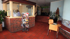 A reception area with a brick counter, a magazine rack, and a seating area with a chair and a small table. - BOLA Kulturhostel (Bochum)