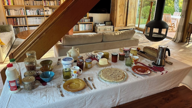 A dining table set with various dishes and utensils, surrounded by bookshelves and a cozy seating area. - Les oliviers room, quiet and bright (Fouesnant)