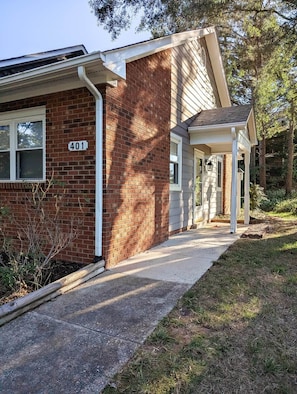 A two-story building with a brick facade, a visible number '401', and a covered porch area. - Stylish One-Level Near RDU | Cozy & Modern (Morrisville)