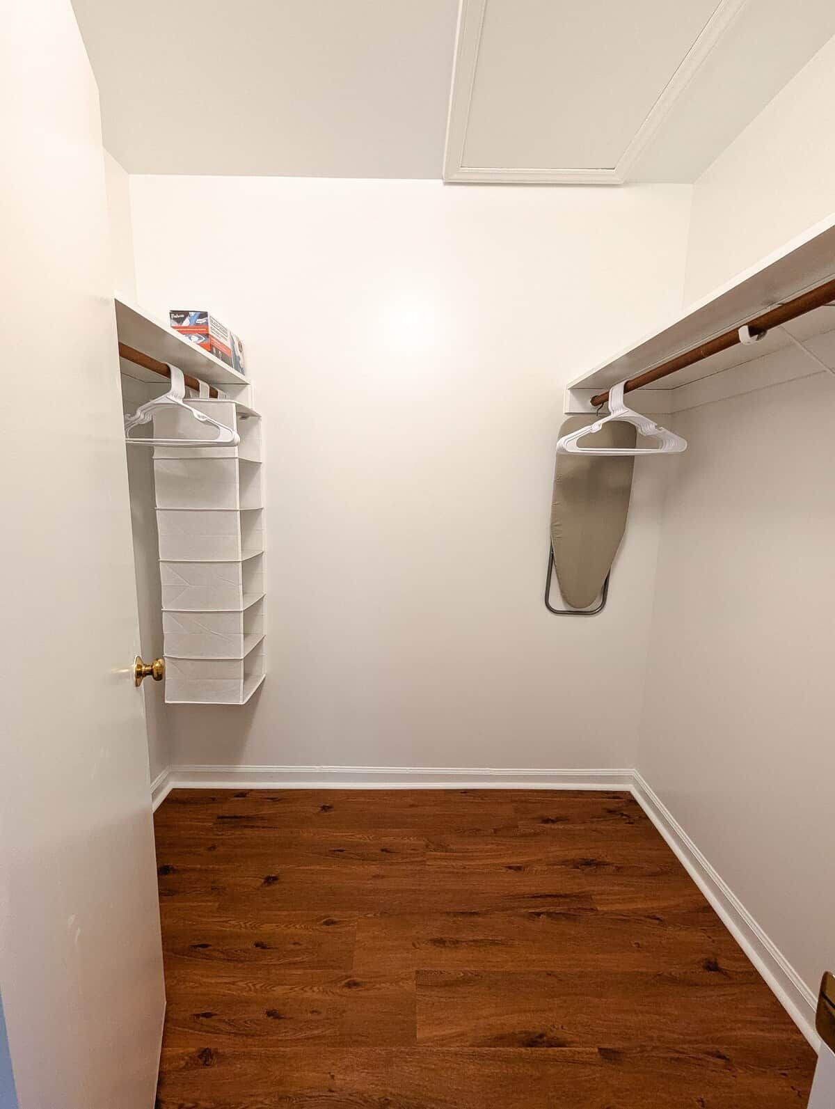 A closet with white hanging organizers and a wooden floor.