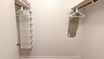 A closet with white hanging organizers and a wooden floor.