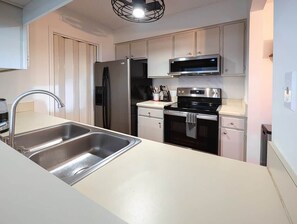 Une cuisine moderne équipée d’un évier en acier inoxydable, d’un four à micro-ondes, d’une cuisinière et d’un réfrigérateur.