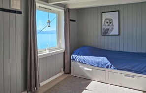 A bedroom with a bed, a window with curtains, a hanging lantern, and a framed owl picture on the wall.