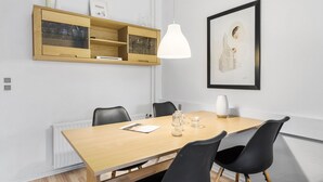 A modern dining area with a wooden table, black chairs, a pendant light, and a framed architectural drawing on the wall. - 1 bedroom lovely apartment in Nexø (Nexø)