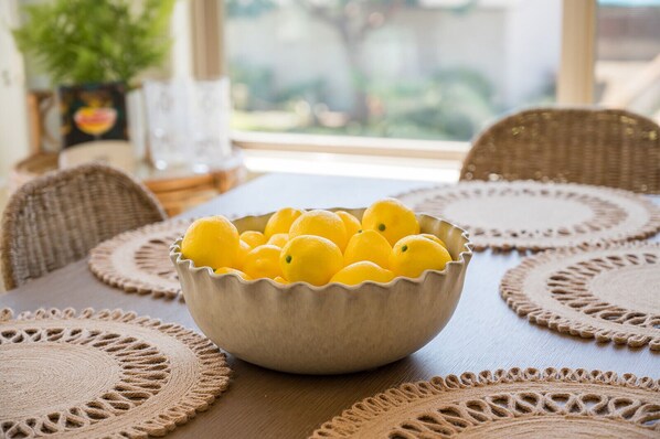 A bowl of lemons on a table with woven placemats.