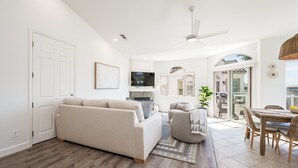 A modern living room with a sofa, armchairs, a TV, and a dining area with a table and chairs. - Two Homes-One block to Beach! (Pismo Beach)