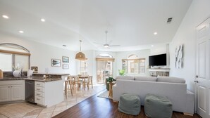 A spacious living area with a kitchen, dining area, and a large gray sofa. - Two Homes-One block to Beach! (Pismo Beach)