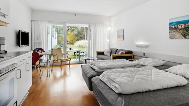 Habitació d'hotel moderna amb cuineta, zona de menjador, sofà i llit.
