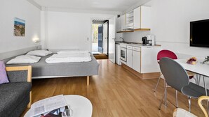 Habitació d'hotel senzilla amb llit, petita cuina, menjador i televisió.