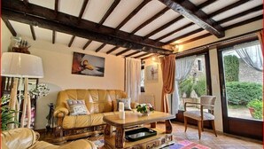A cozy living room with a leather sofa, a wooden coffee table, and a view of the garden through a glass door.