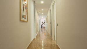 A hallway with a polished tile floor, white walls, and framed artwork.