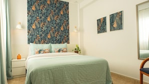 A bedroom with a bed, nightstand, lamp, and two framed pictures on the wall.