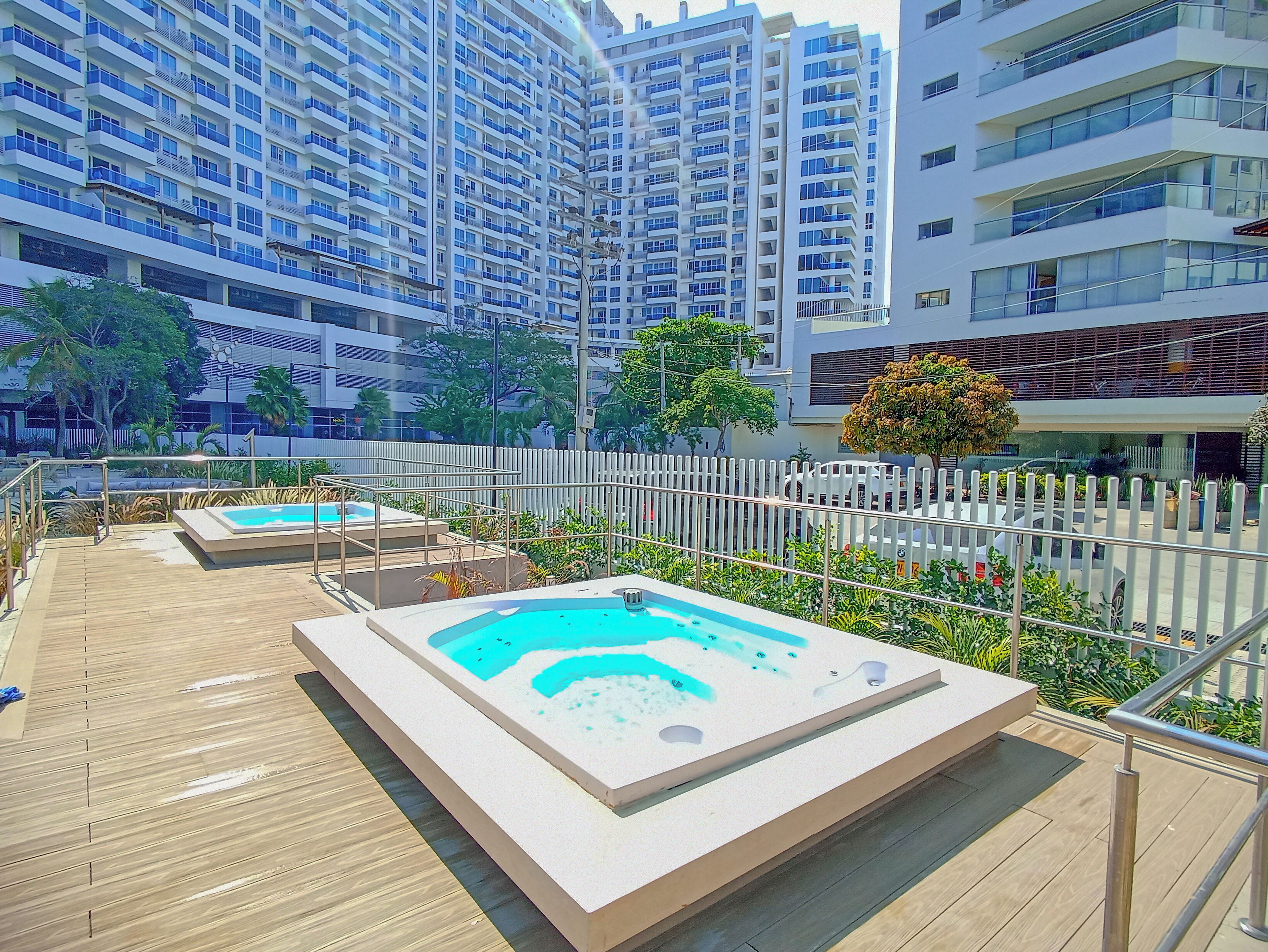 Un área de piscina en la azotea con terraza de madera y jacuzzi.