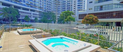 Un área de piscina en la azotea con terraza de madera y jacuzzi.