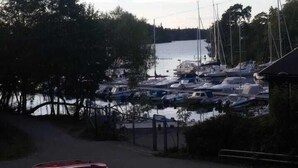 Un puerto deportivo con varias embarcaciones amarradas, rodeado de árboles y una masa de agua.