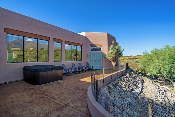 A modern building with large windows, a hot tub, and outdoor seating.