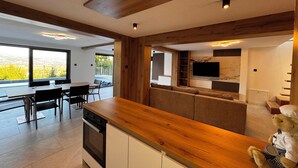 Una cocina moderna con vigas de madera, un comedor con vistas y una zona de estar acogedora con televisión.