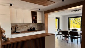 Una cocina moderna con encimera de madera, armarios blancos y una zona de comedor con mesa y sillas.