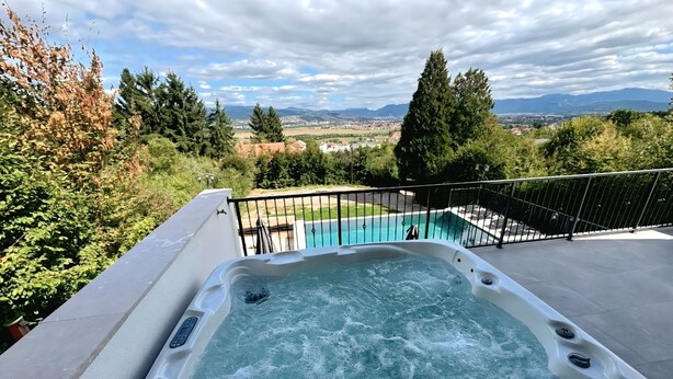 Un jacuzzi con vista a una piscina y un paisaje lejano.
