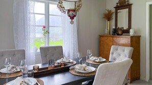 Une salle à manger avec une table dressée pour quatre personnes, un lustre et un miroir au-dessus de la table.