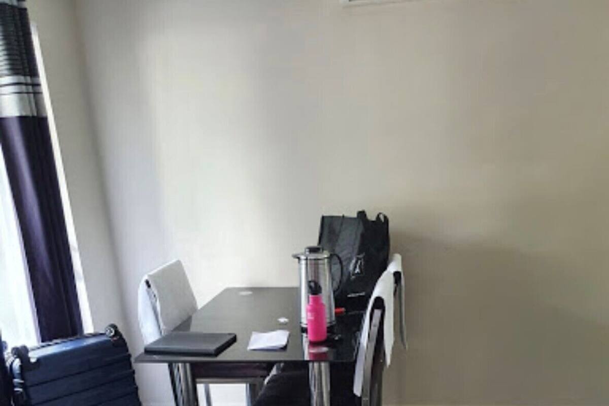 A small, simple room with a table, a chair, a suitcase, and a bag.